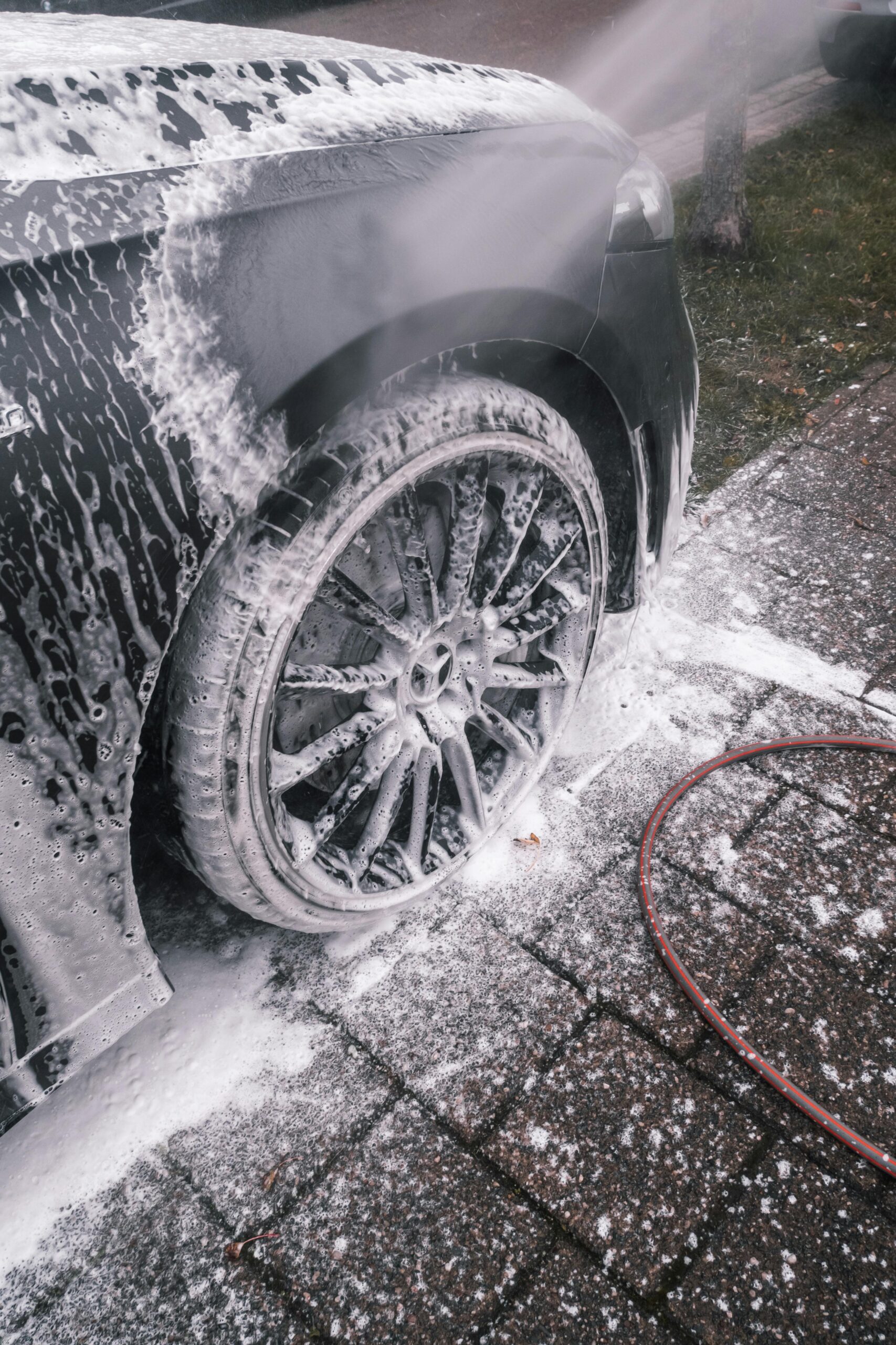 Services Close-up of a luxury car wheel being thoroughly washed with foam outdoors.